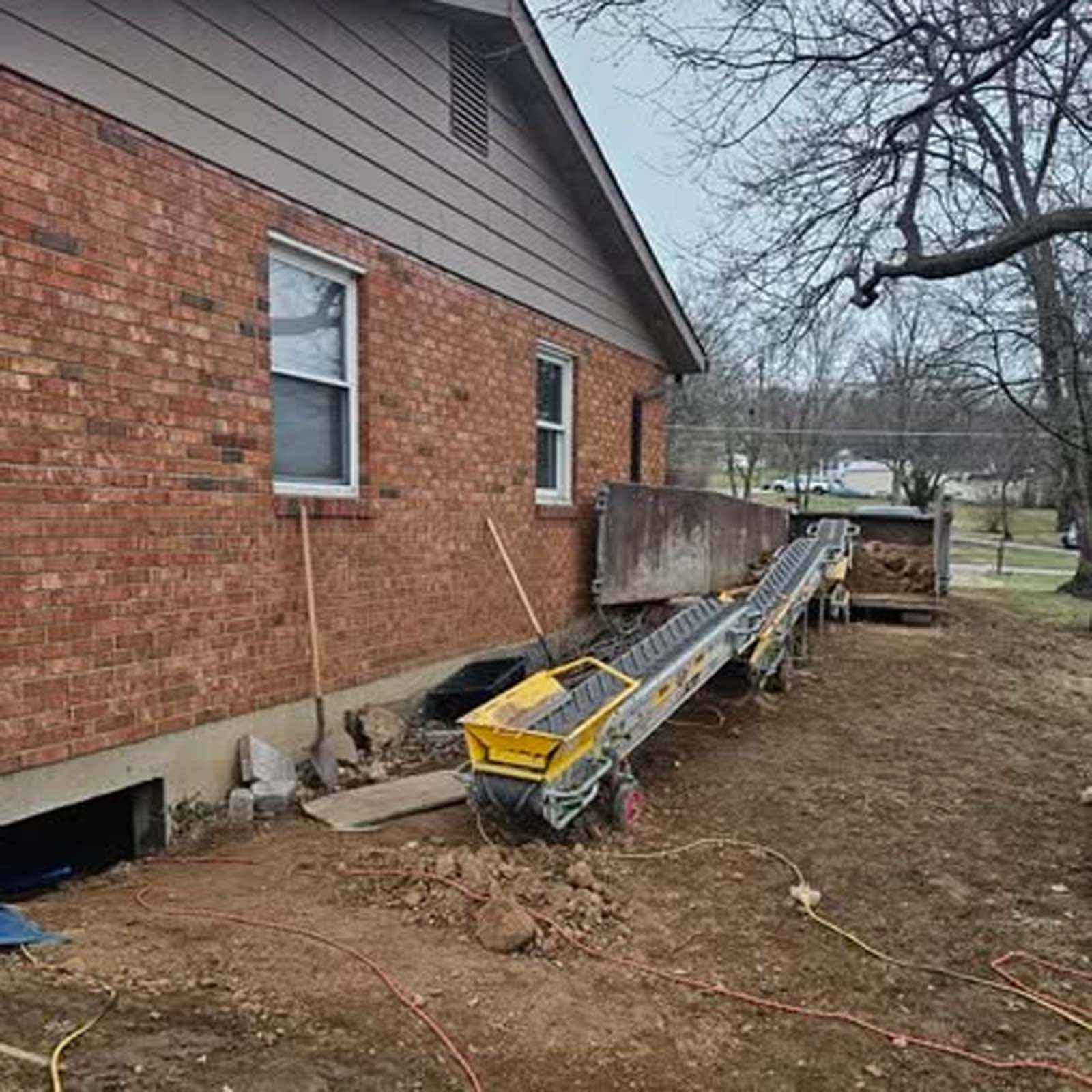 A conveyor belt is sitting in front of a brick house.