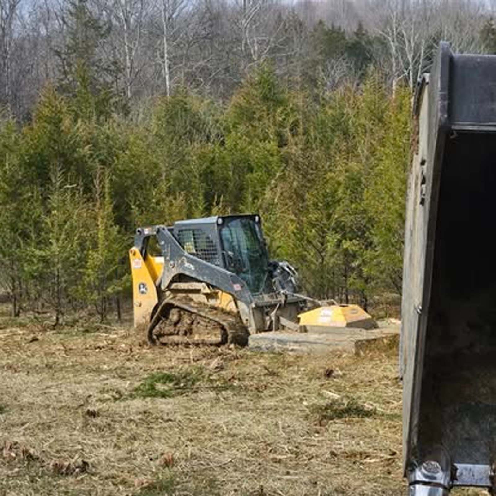 A bulldozer is sitting in a field next to a bucket.
