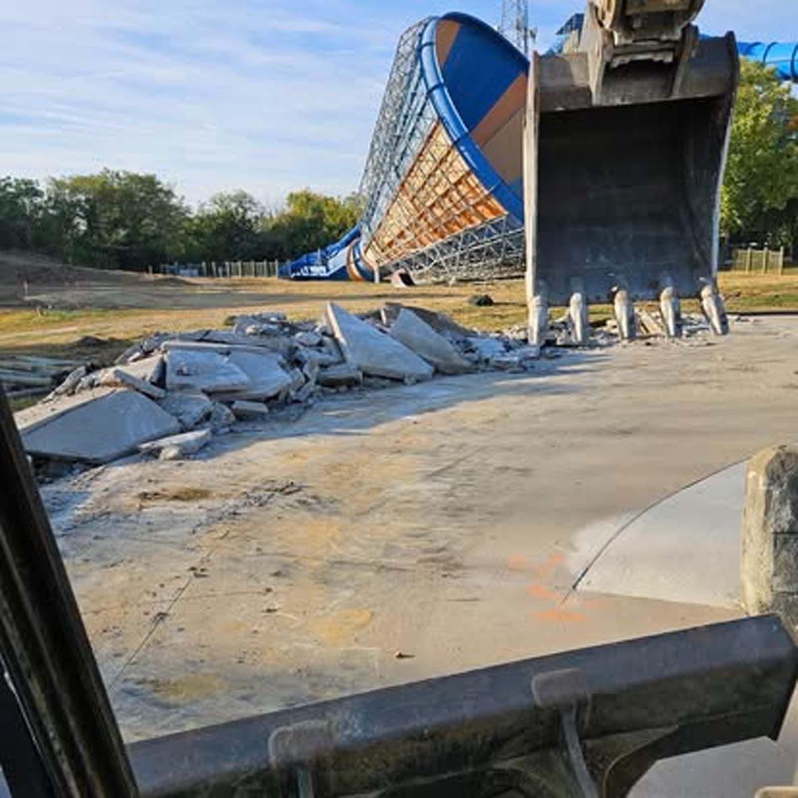 A large water slide is being demolished by a bulldozer.