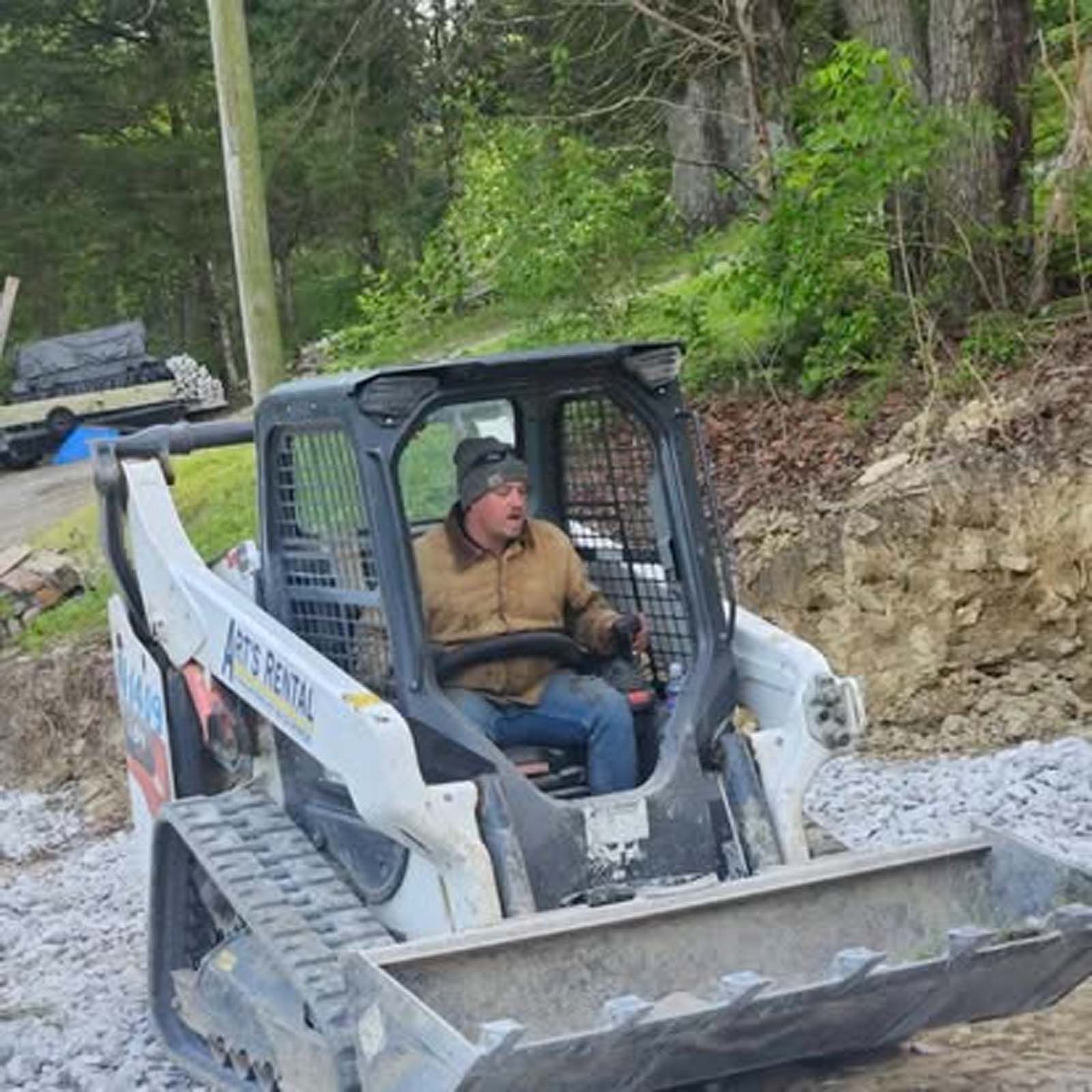 A man is driving a bulldozer on a gravel road.