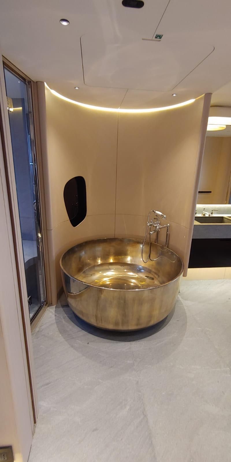 Un bagno con una vasca rotonda dorata al centro della stanza.