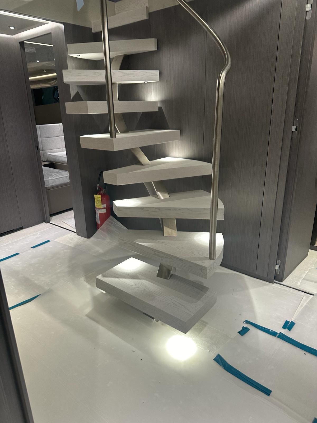 Una scala a chiocciola è appoggiata su un pavimento bianco in una stanza.