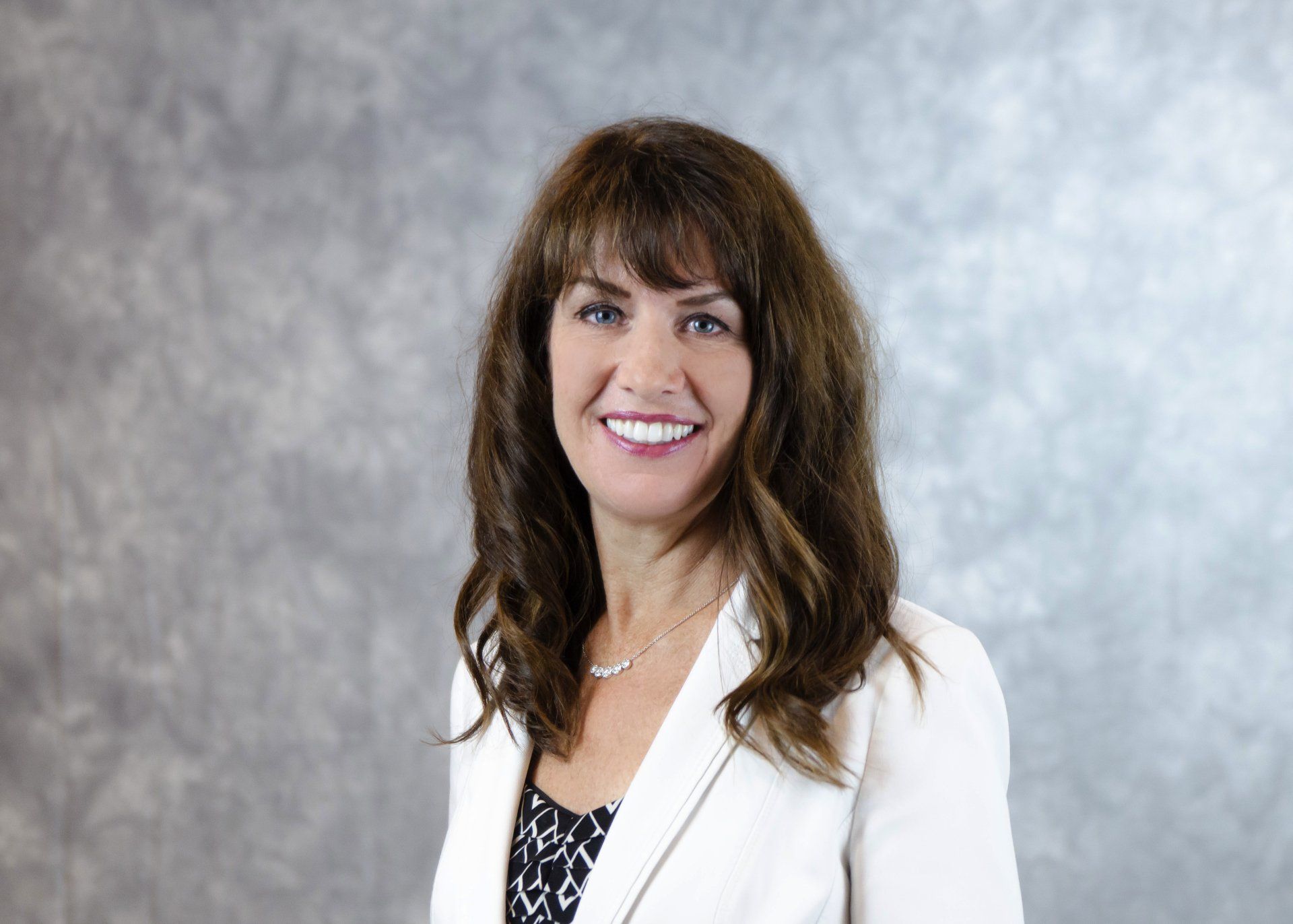 A woman in a white jacket is smiling for the camera.