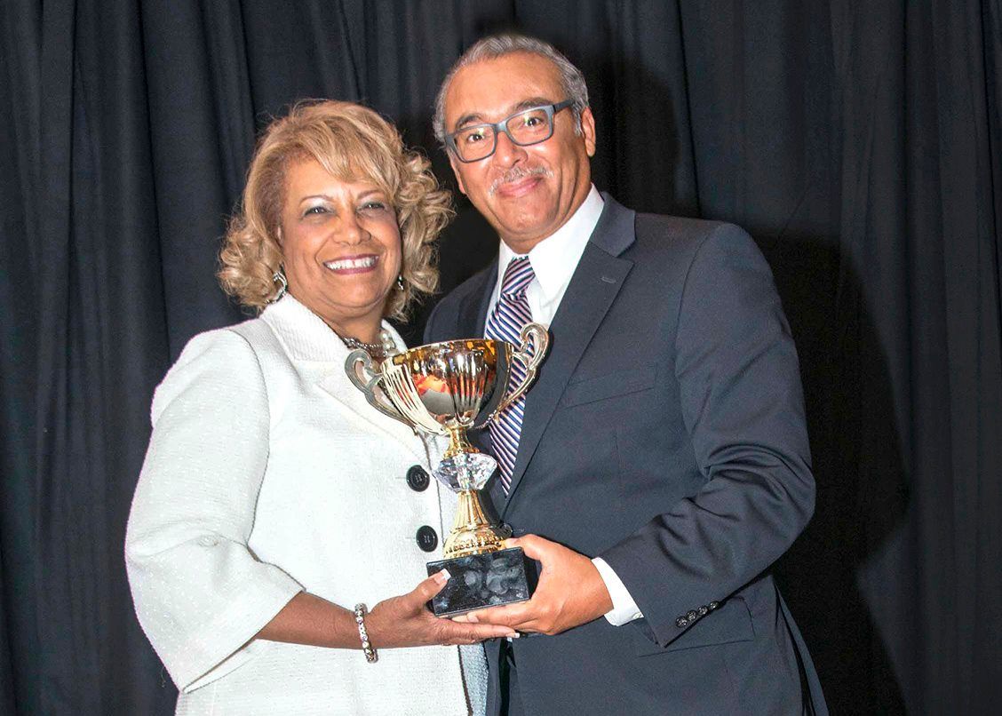 A man and a woman are posing for a picture while holding a trophy.