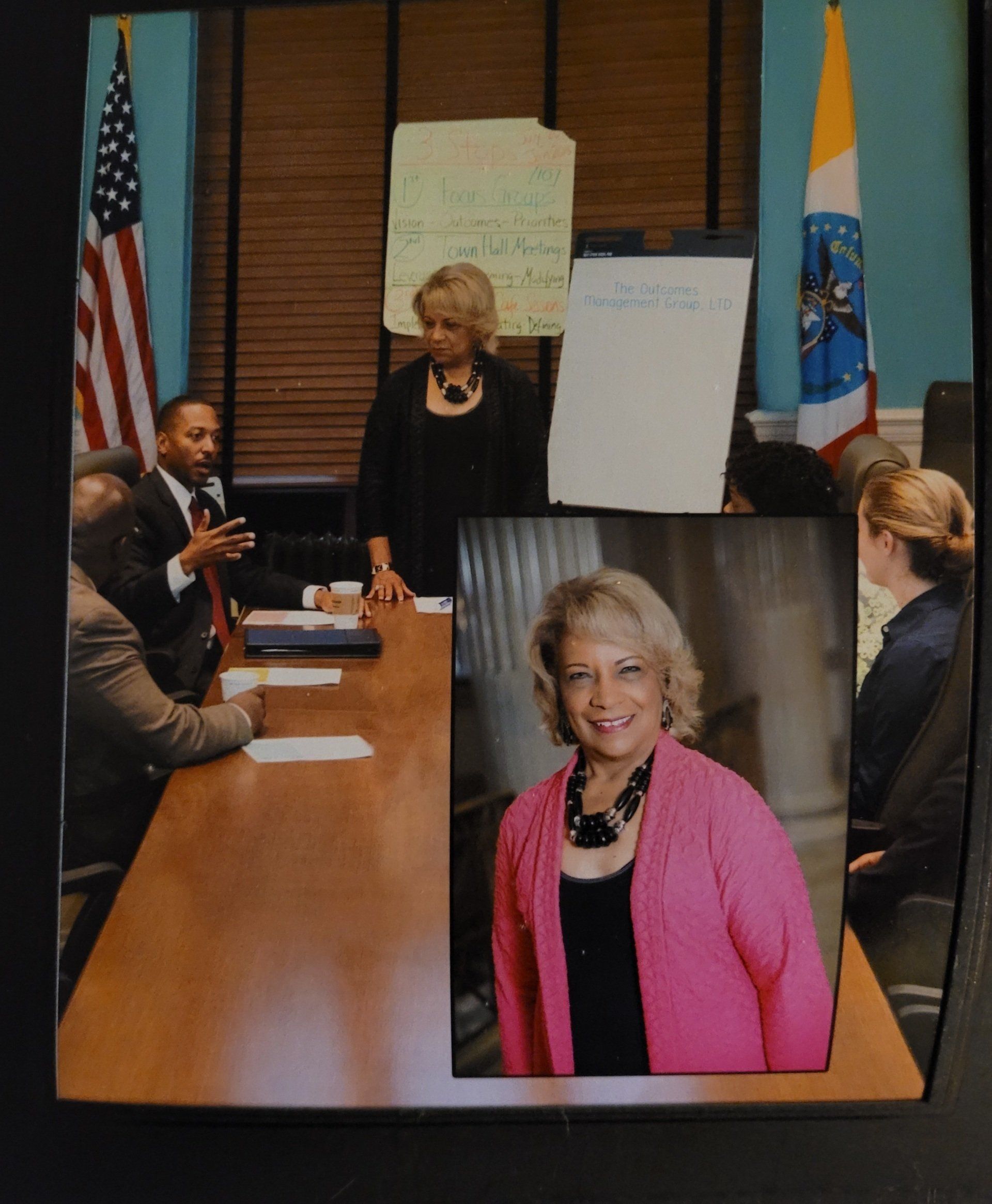 A woman in a pink jacket stands in front of a group of people