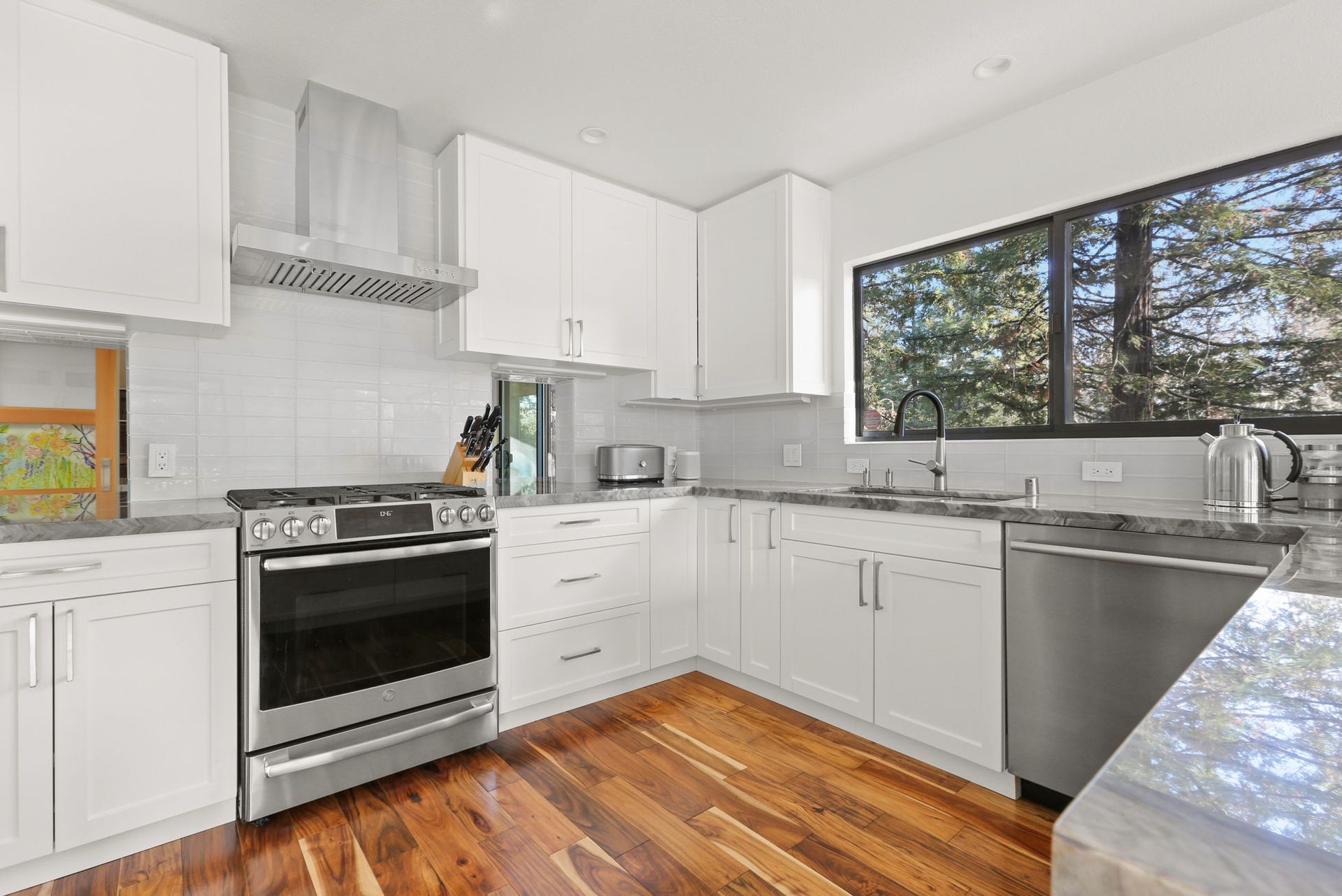 A kitchen with white cabinets , stainless steel appliances , and hardwood floors.