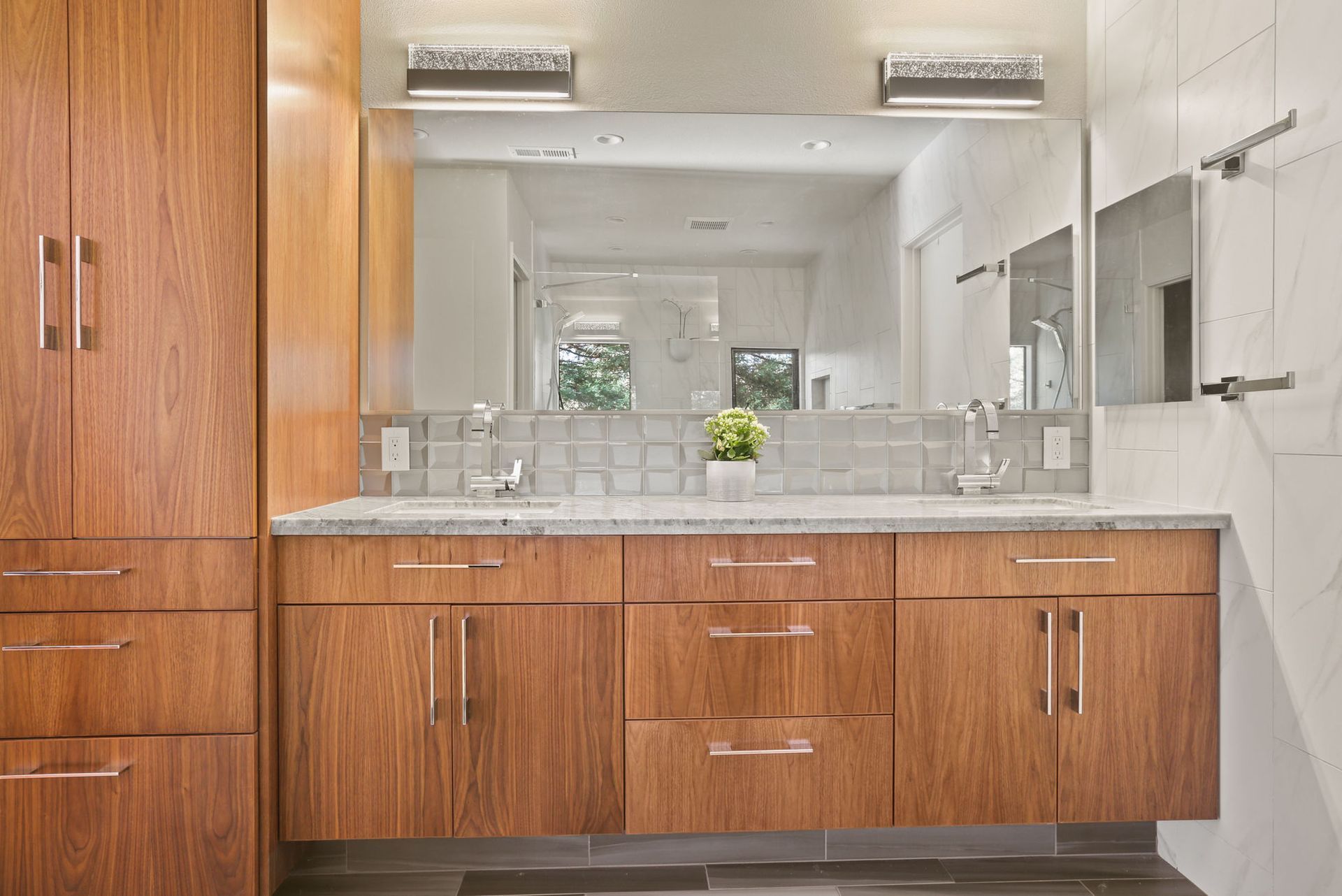 A bathroom with two sinks , a large mirror and wooden cabinets.