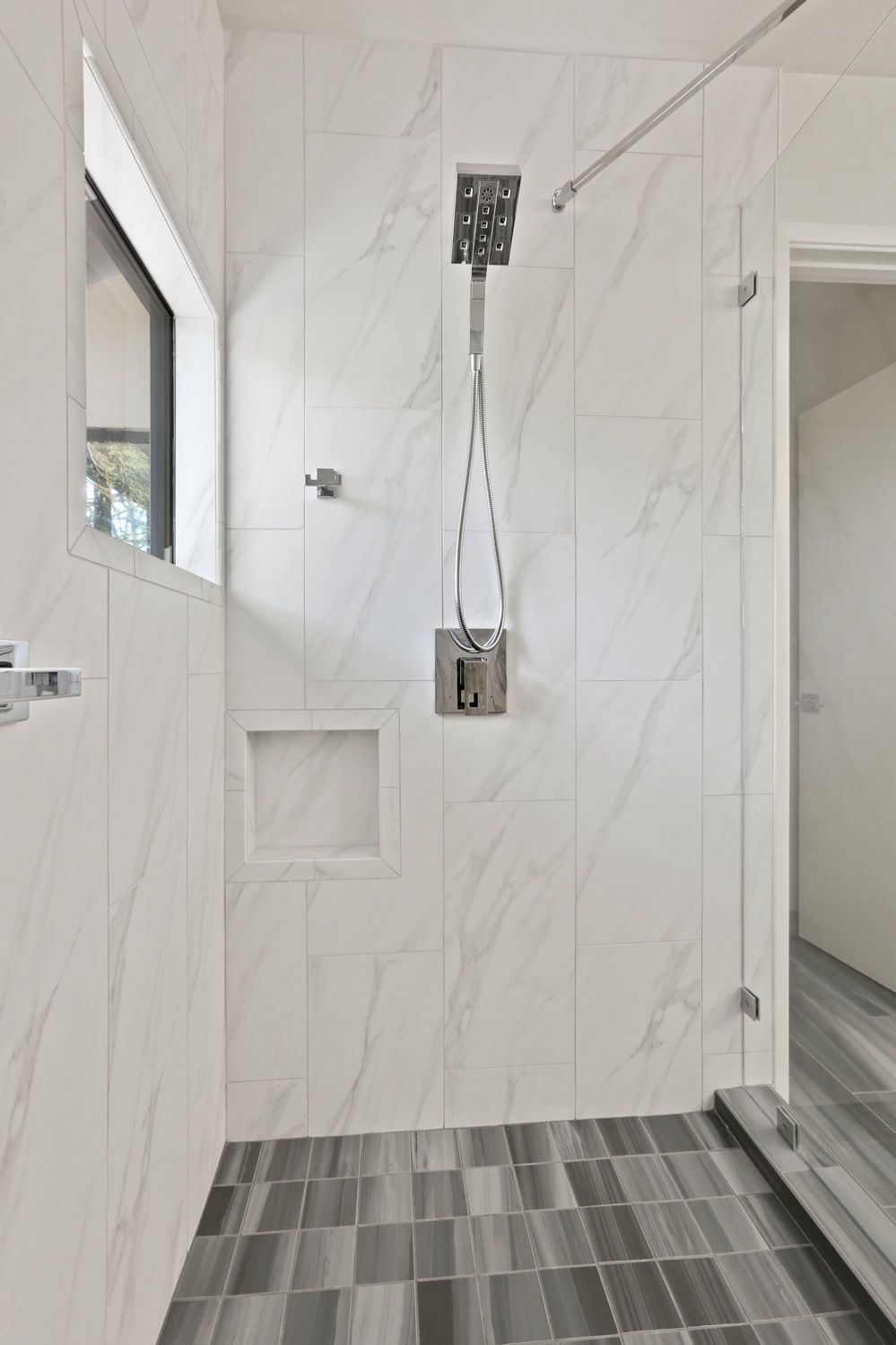 A bathroom with a walk in shower and a window.