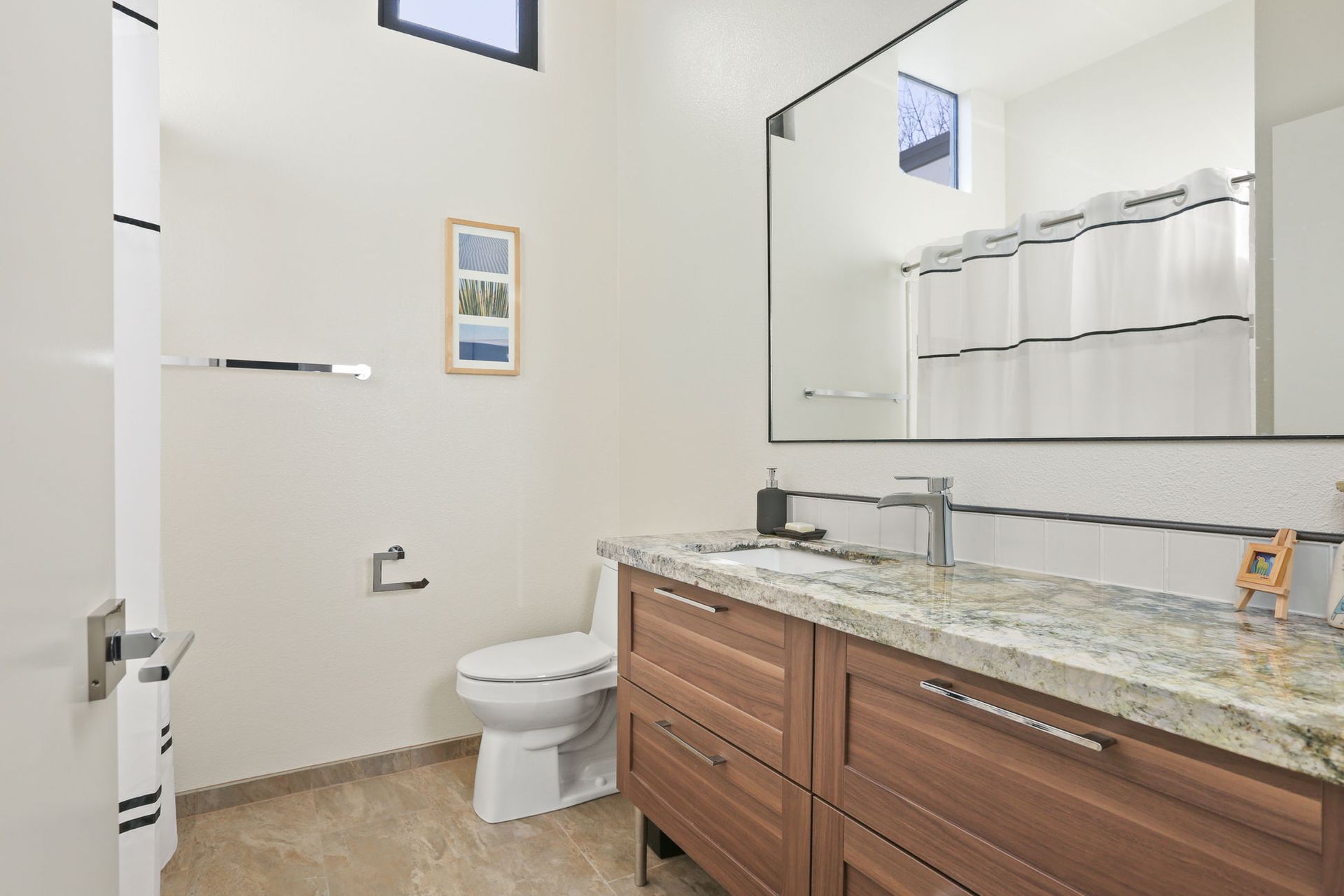 A bathroom with a toilet , sink and mirror.