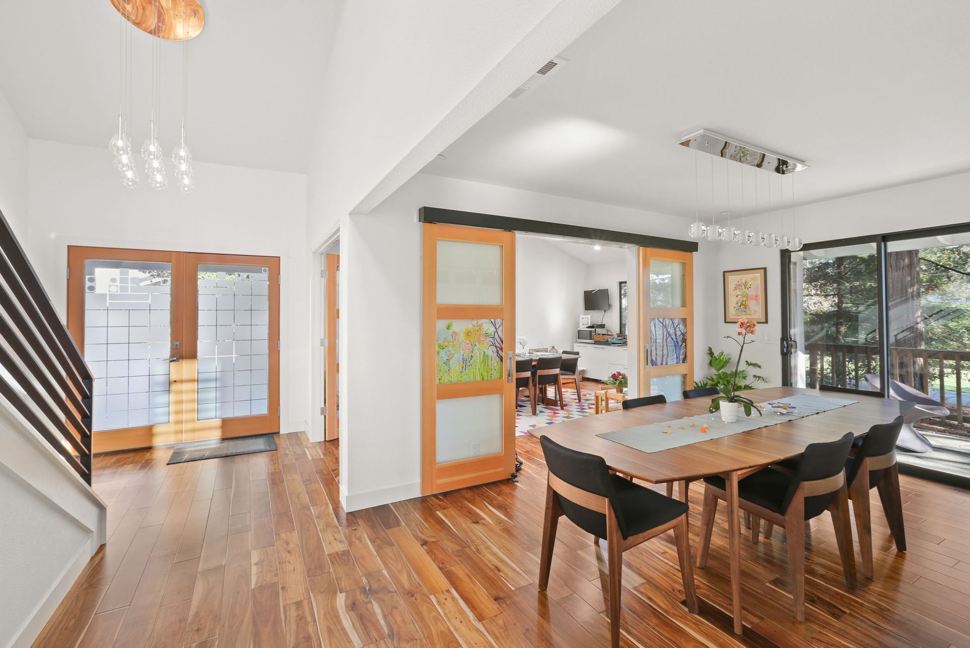 A dining room with a wooden table and chairs and sliding glass doors.