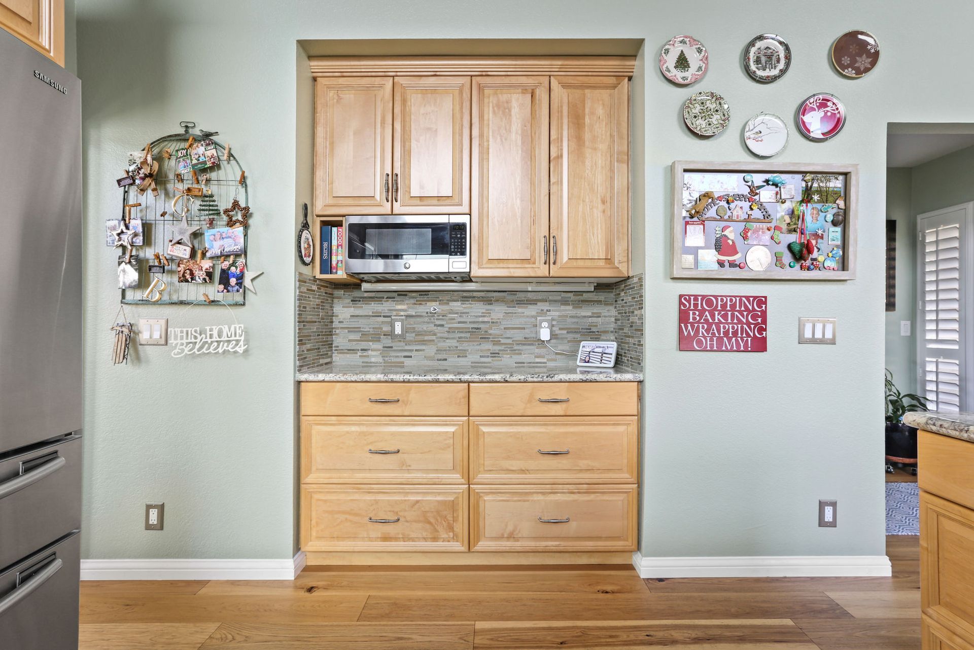 A kitchen with wooden cabinets , a microwave , and plates on the wall.