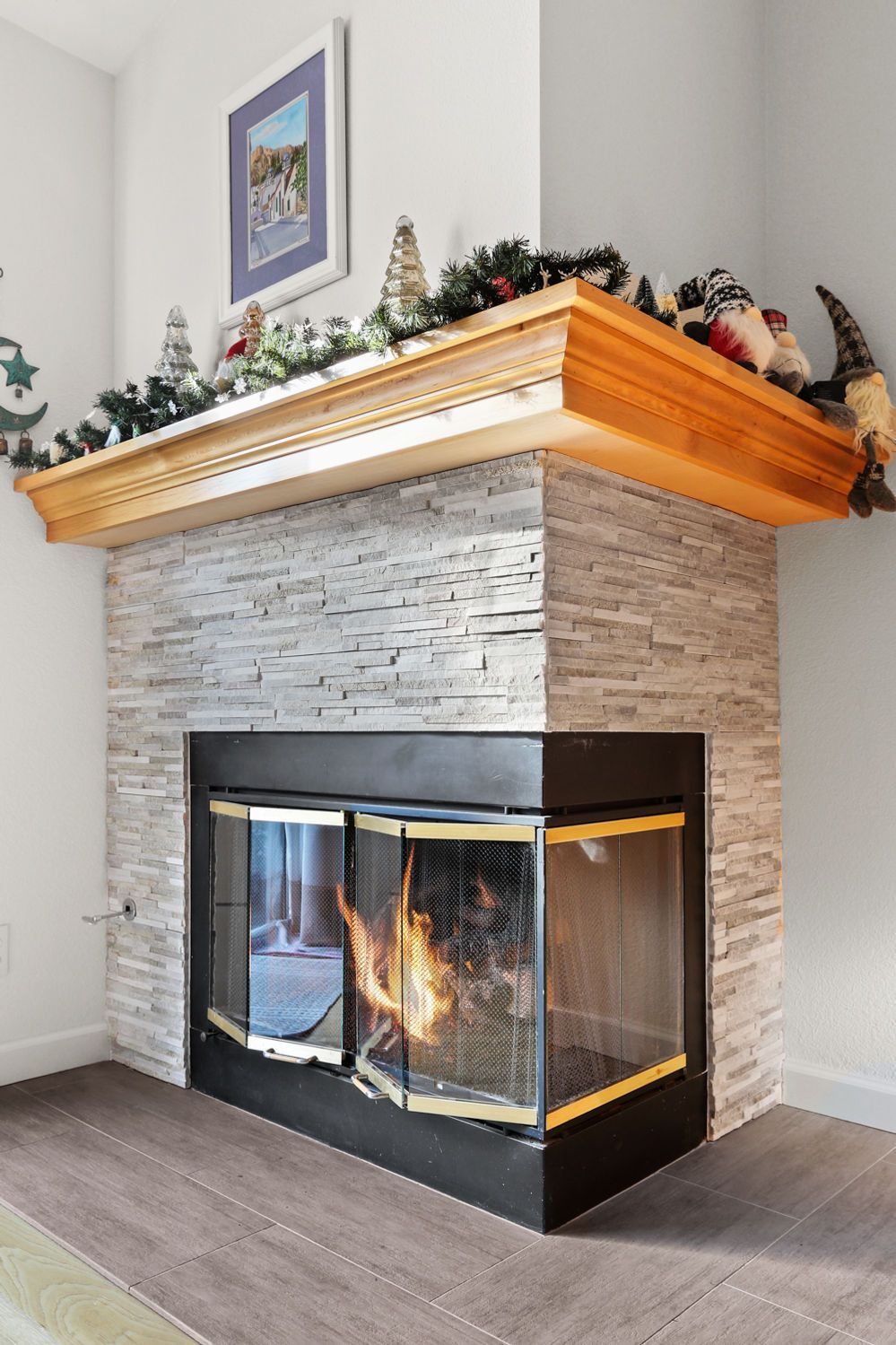 A living room with a fireplace and a mantle decorated for christmas.