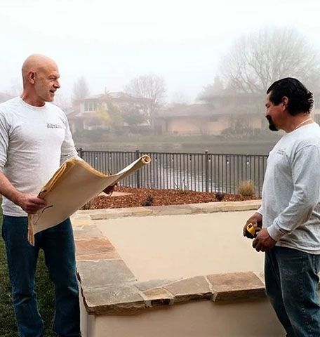 Two men are standing next to each other looking at a blueprint.