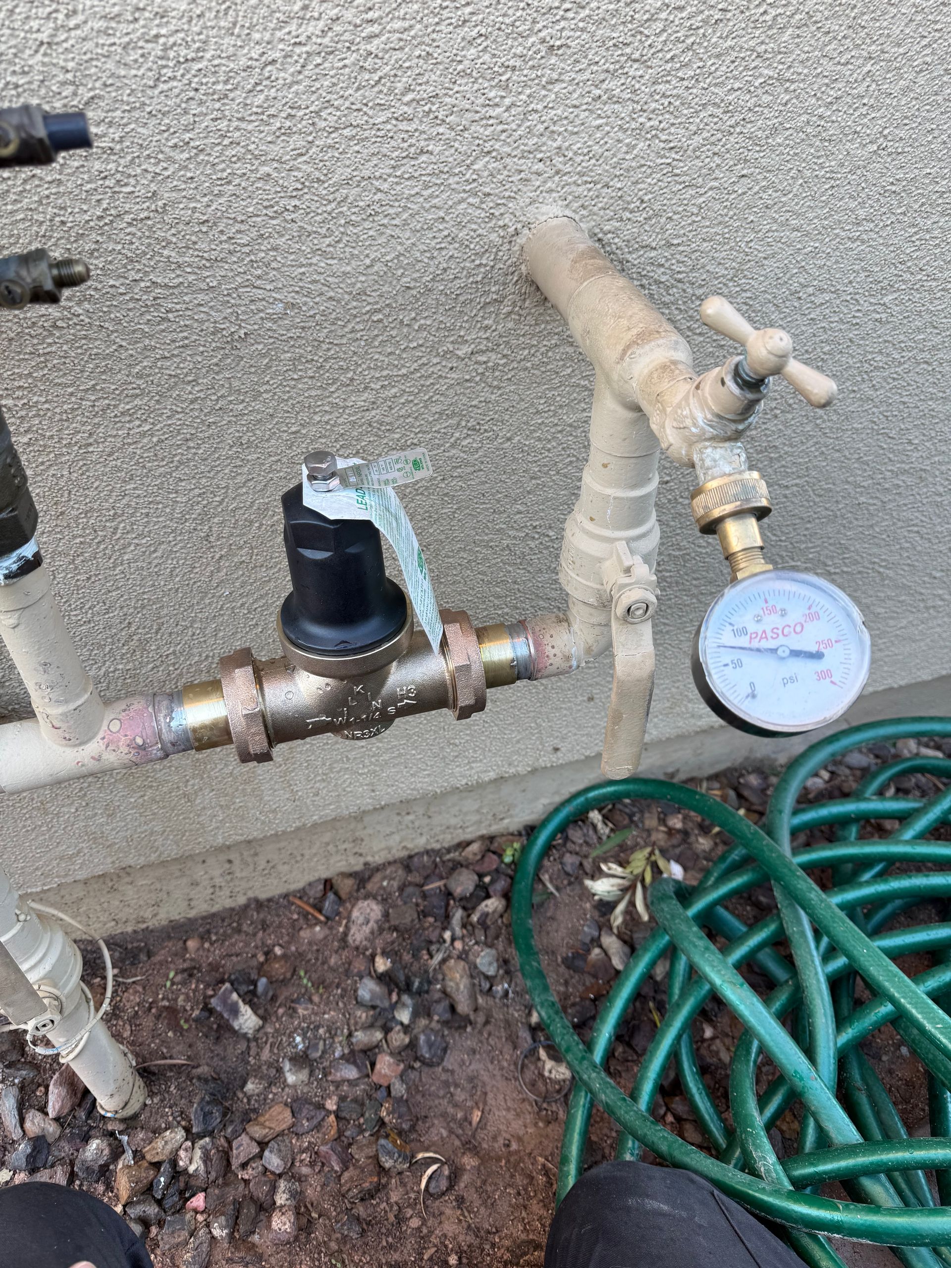 Outdoor water pipes with a pressure gauge and hose.