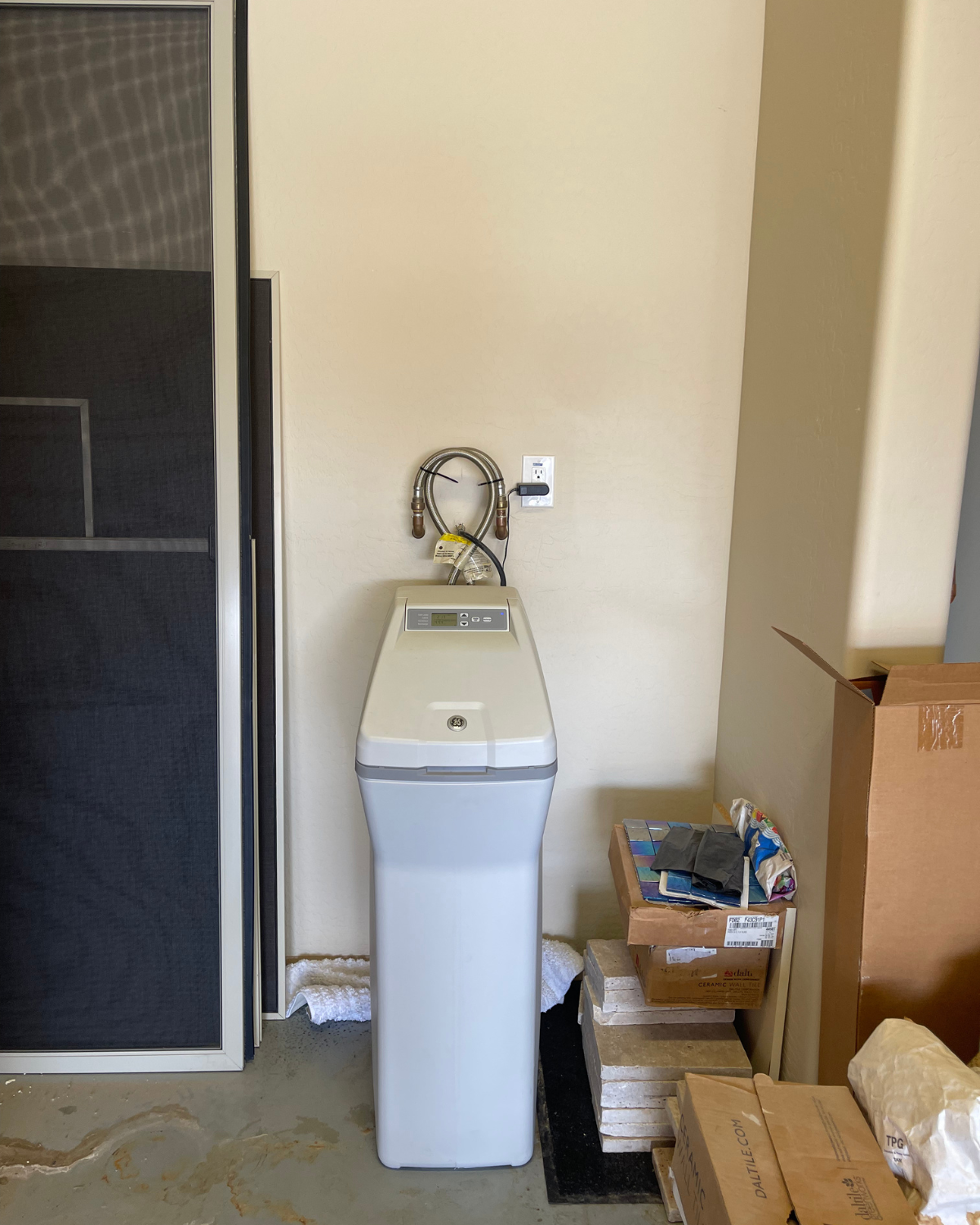 A water softener is sitting in a corner of a room.