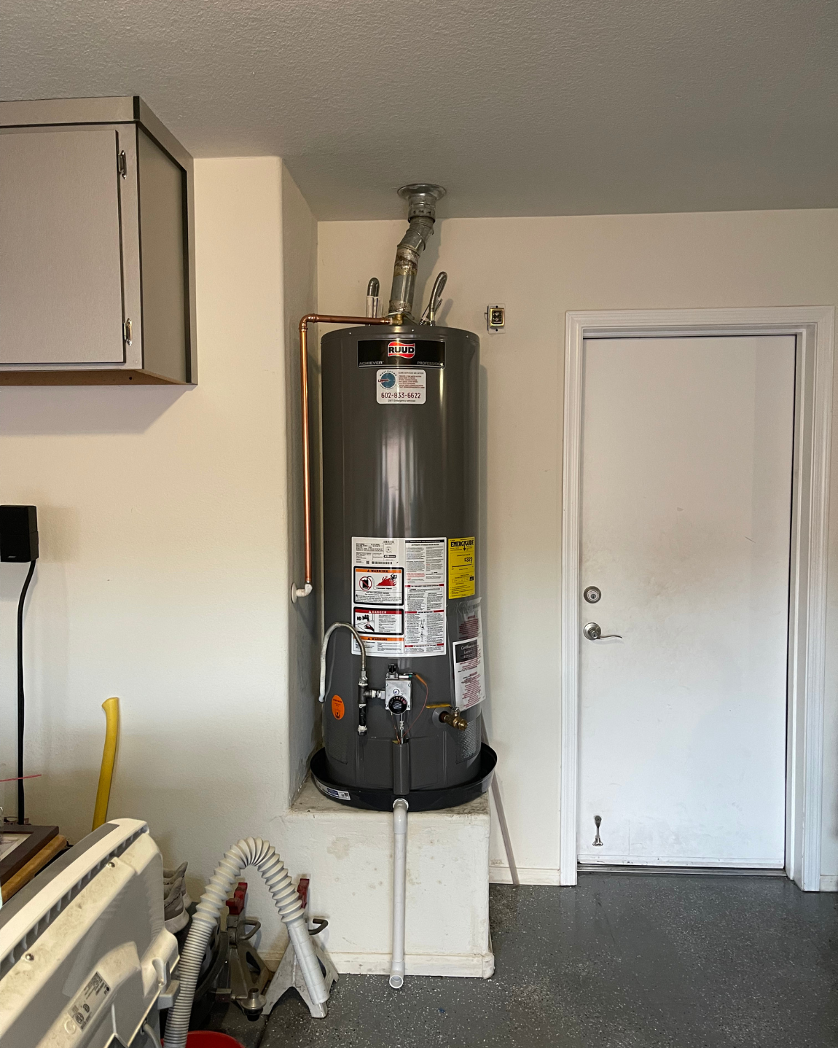 A water heater in a garage next to a door