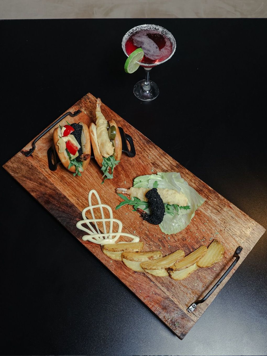 Due persone che tengono bicchieri di vino e un piatto di cibo davanti a un cartello che dice la playa