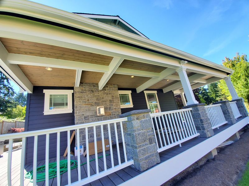 Dark house with white porch and stone accents.
