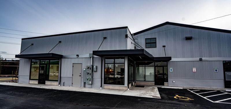 Exterior view of a modern building with metal siding, glass windows, and a dark awning.
