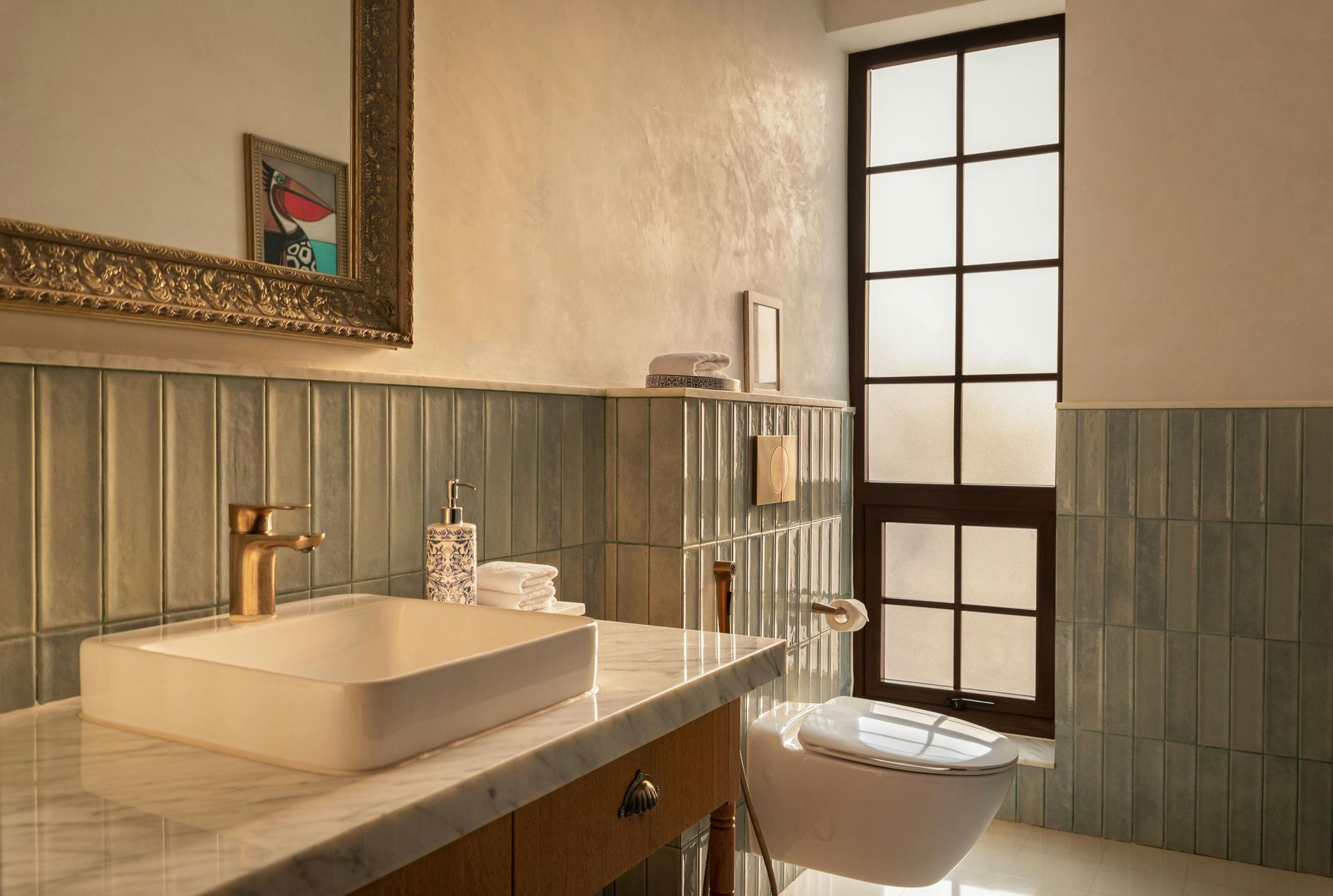 Bathroom with gold fixtures, teal tiles, a white sink, and a window with frosted glass.