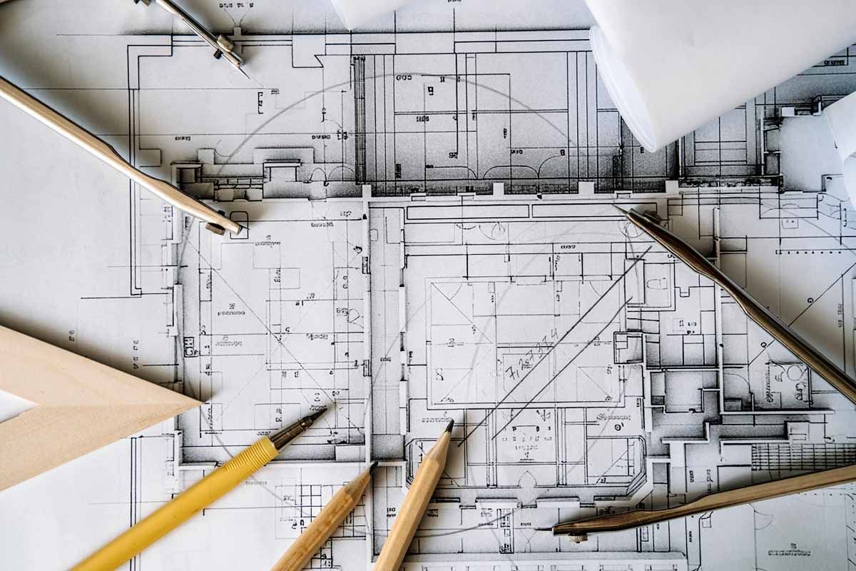 Architectural blueprints with drafting tools on a white surface.