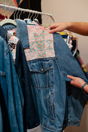 A person is holding a denim jacket in their hand.