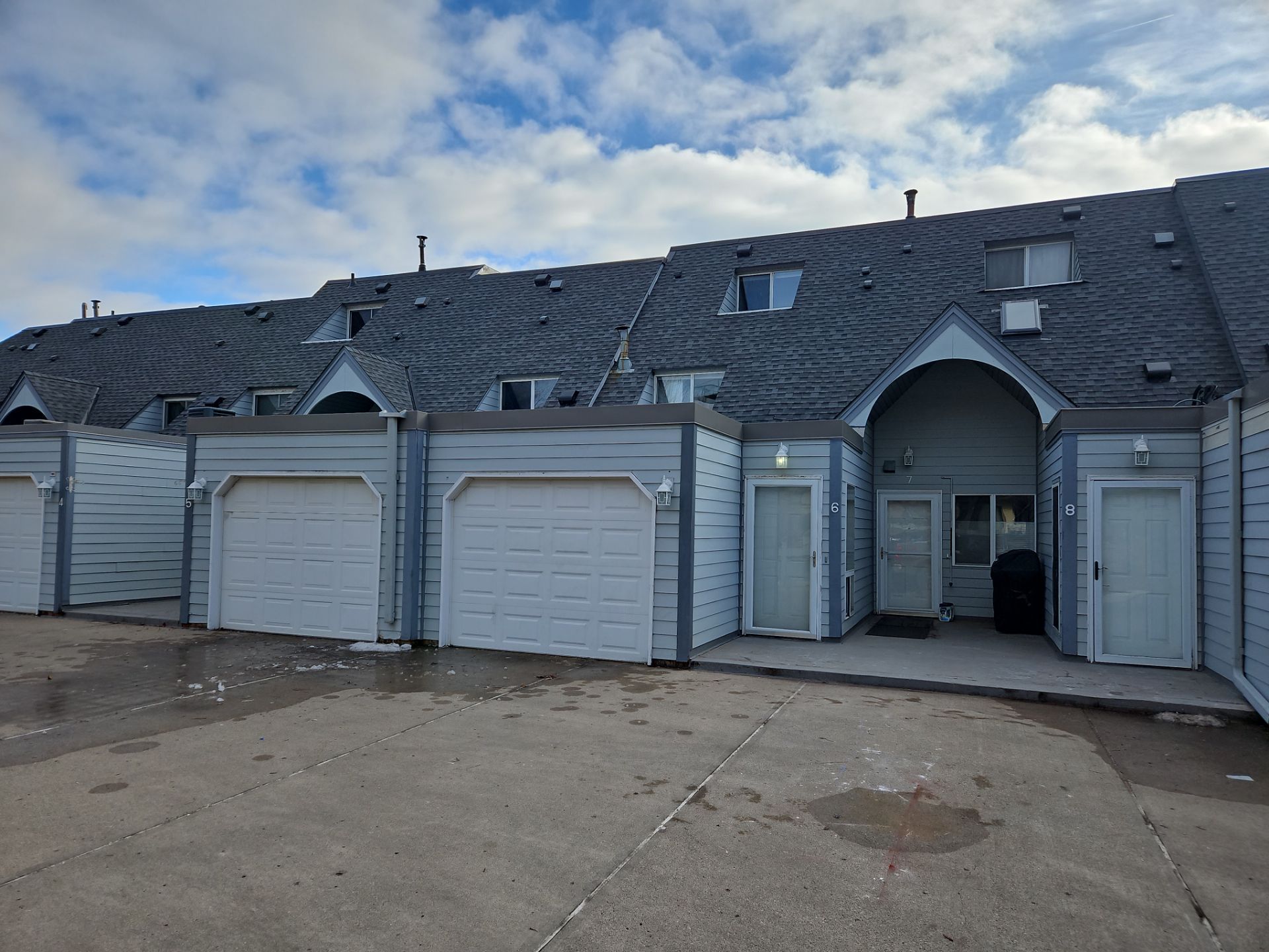 a row of houses with a gray roof and white garage doors .