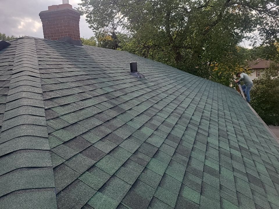 a man is standing on top of a green roof .
