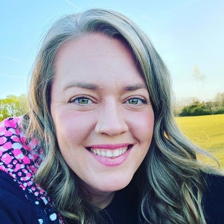 A woman is smiling for the camera in a field.