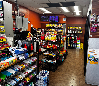Interior of a convenience store: shelves of snacks, drinks, and automotive products, near a checkout counter.