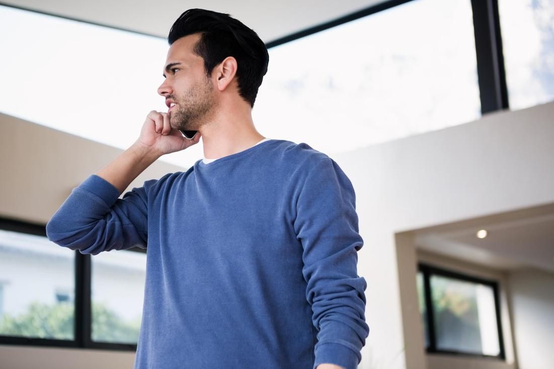 A man in a blue sweater is talking on a cell phone.