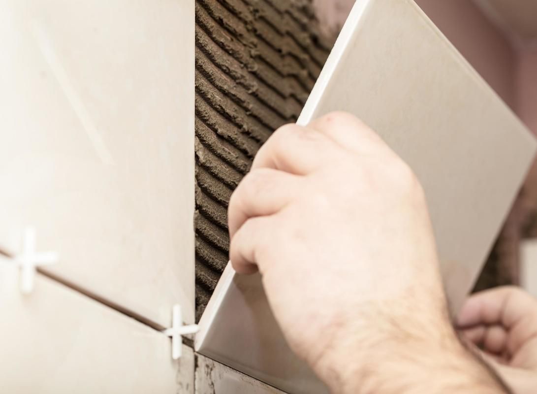 A person is laying tiles on a wall.