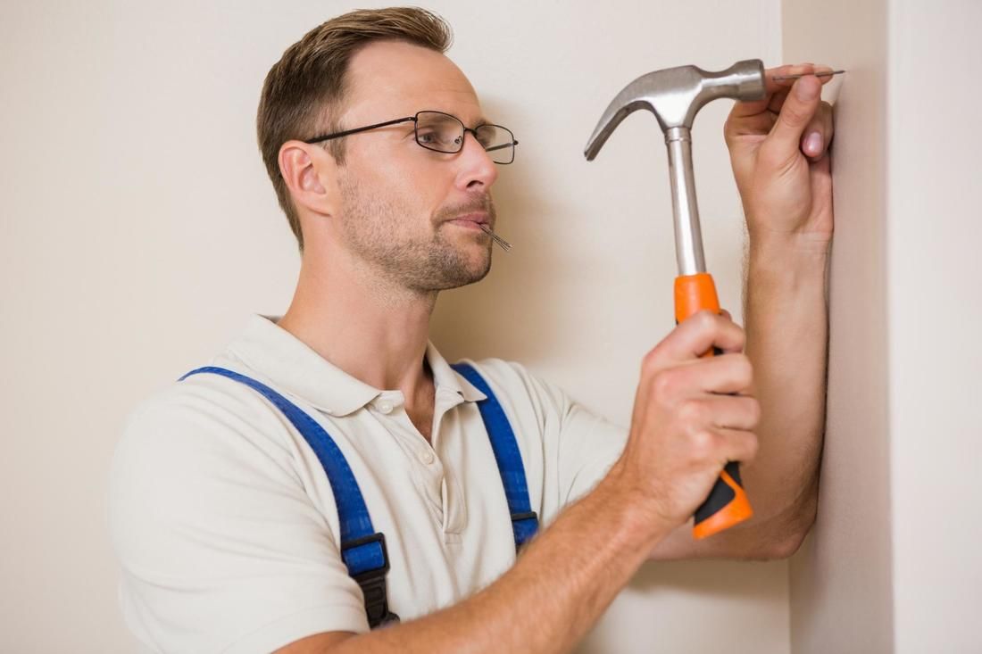 A man is hammering a nail into a wall.