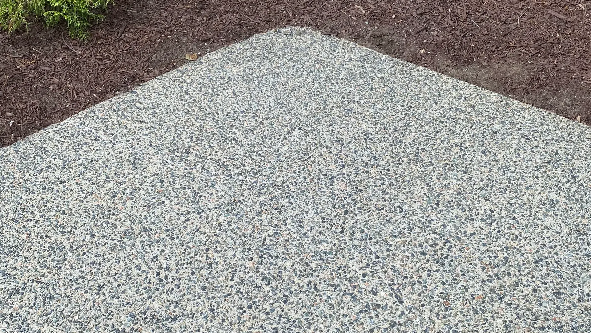 Triangular gray gravel path bordered by brown mulch.