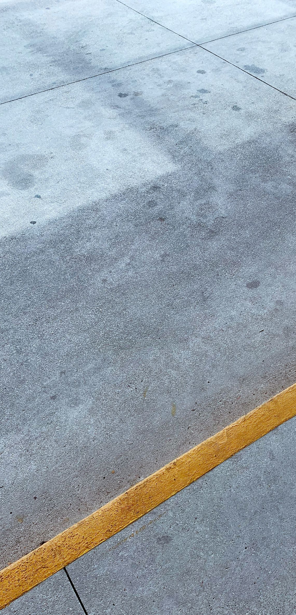 Close-up of textured gray pavement with a diagonal yellow line marking.