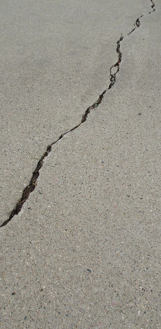 A diagonal crack running through a gray concrete surface.