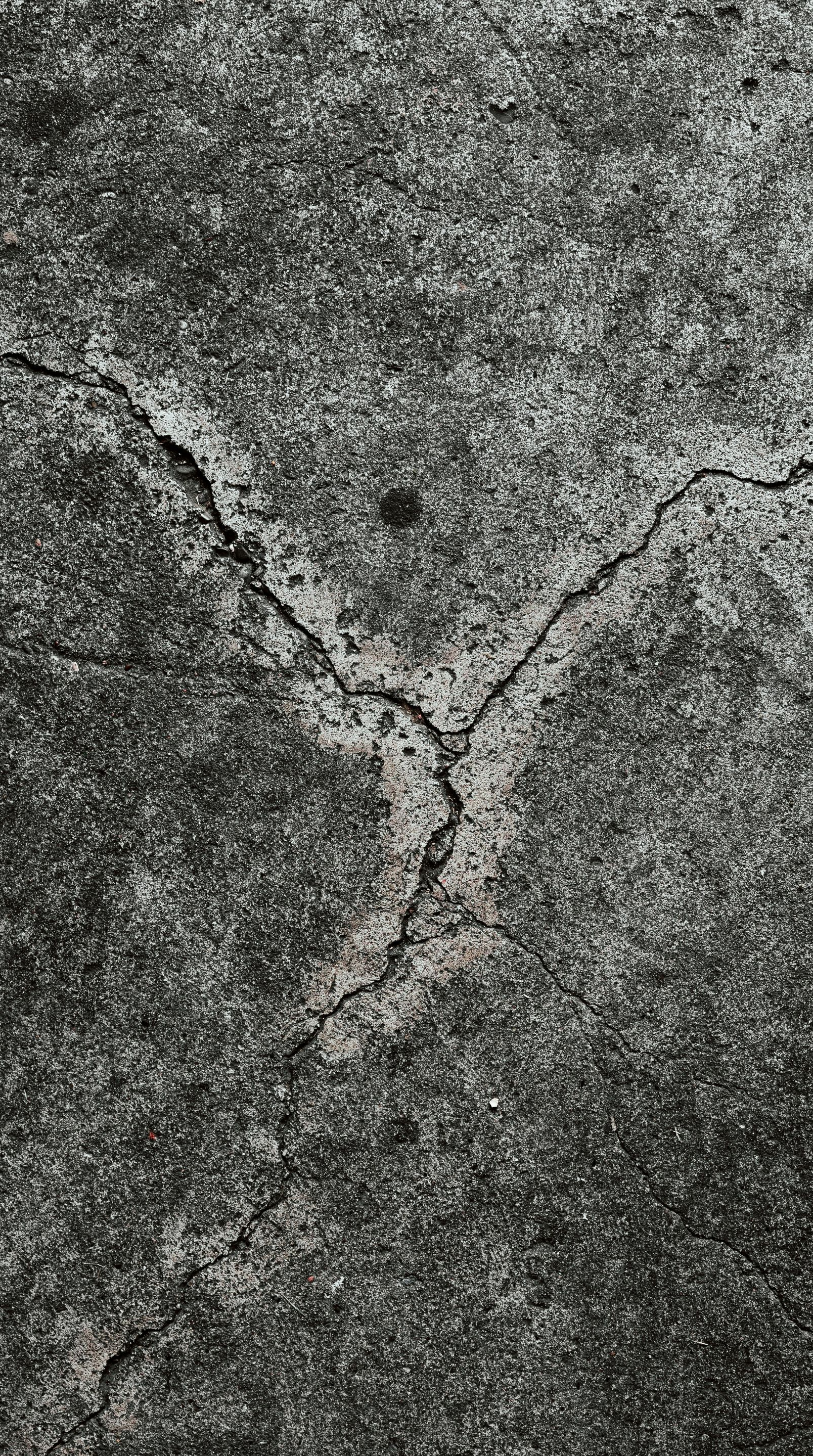 Cracked gray concrete surface with dark patches.