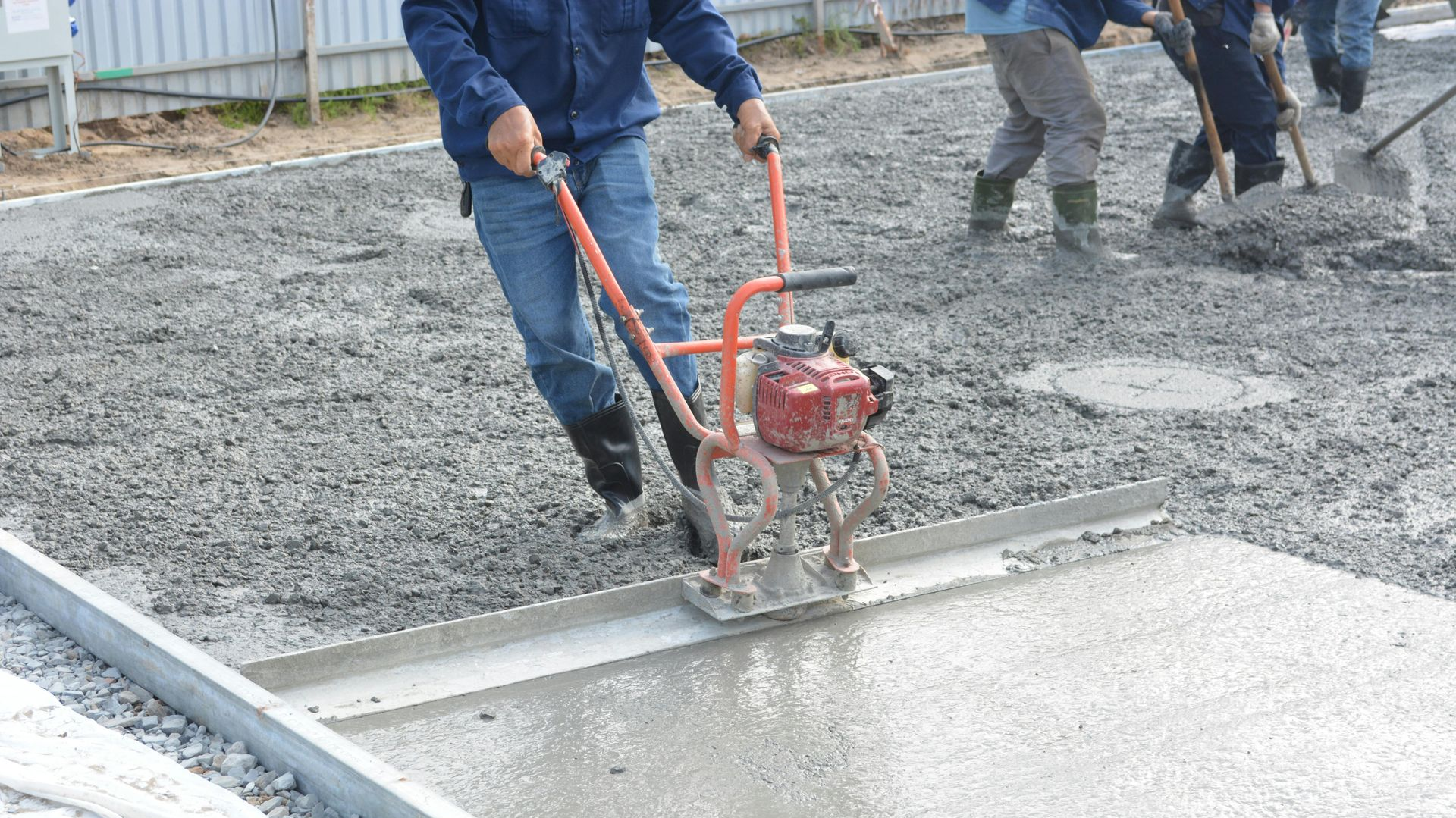 Worker smoothing wet concrete with a power trowel on a construction site