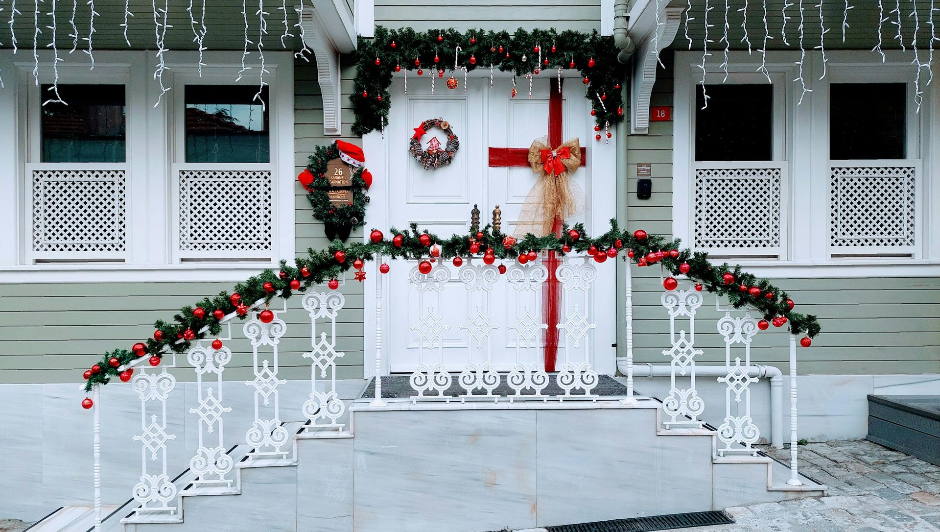 Christmas decorated house exterior with garlands, wreaths, and red accents.