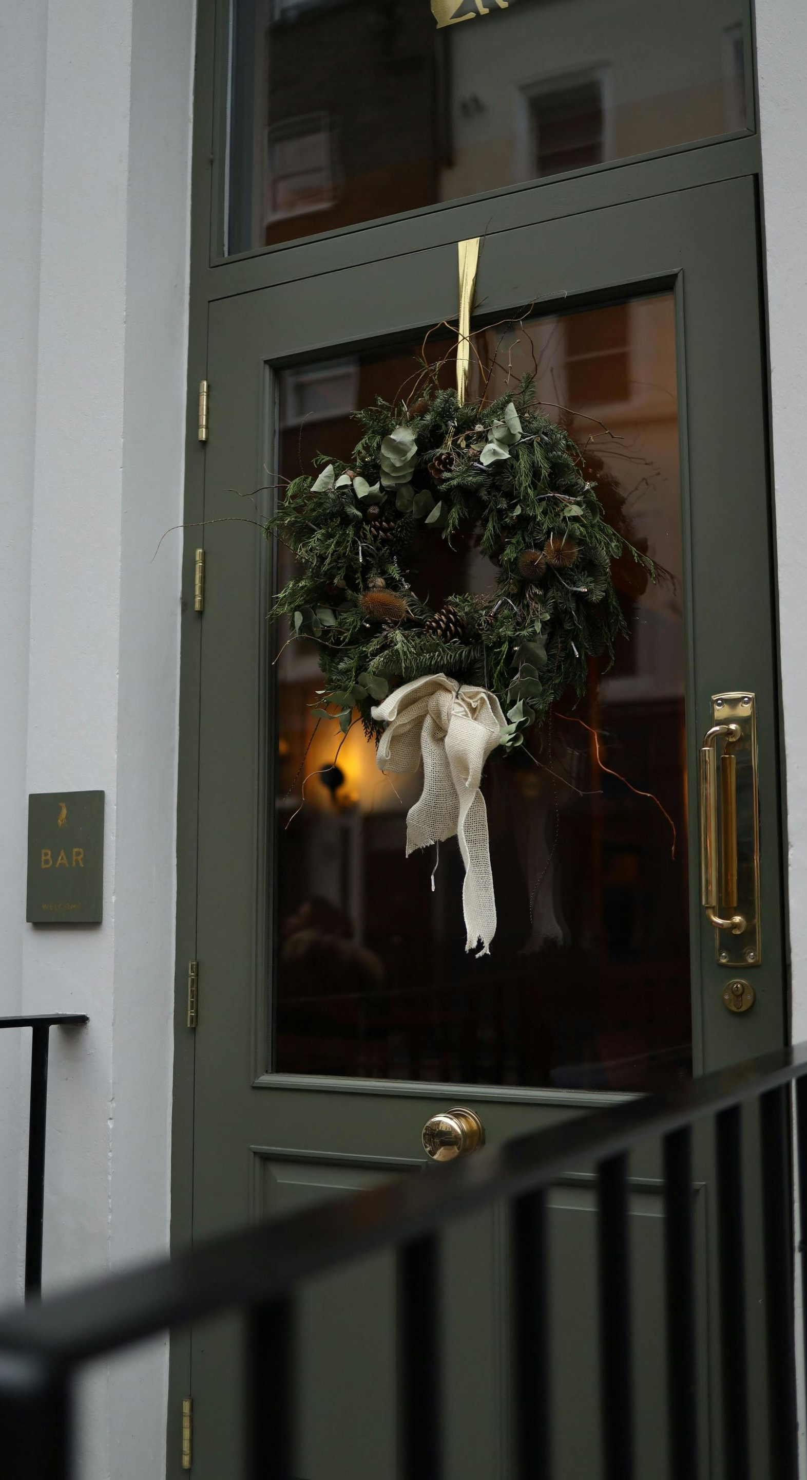 Green door with holiday wreath and gold hardware.