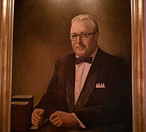 A field of red and yellow flowers with a sunset in the background.
