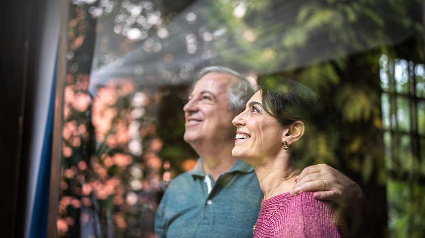 A man and a woman are looking out of a window.