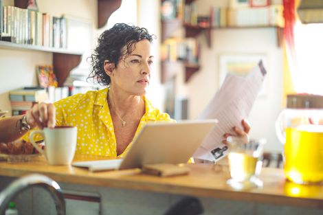 A woman is sitting at a table with a laptop and a cup of coffee.