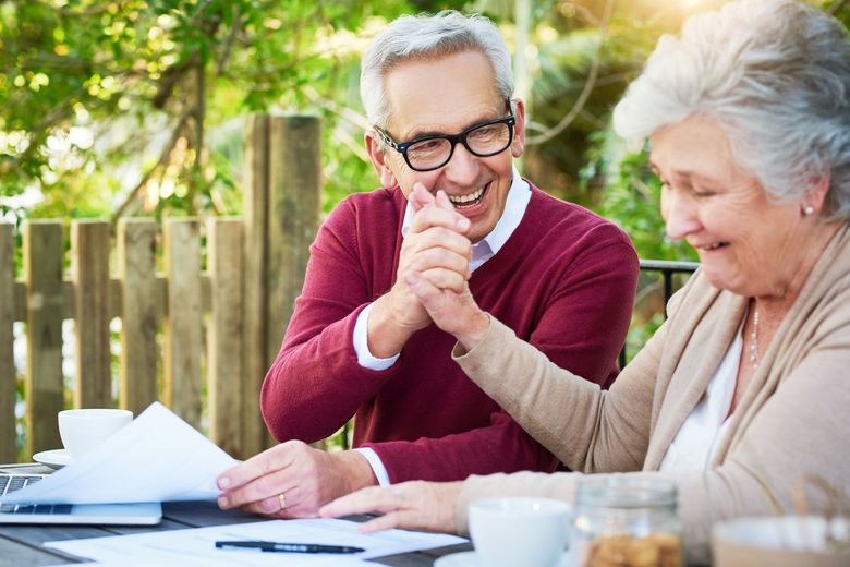 An elderly couple is sitting at a table looking at papers.
