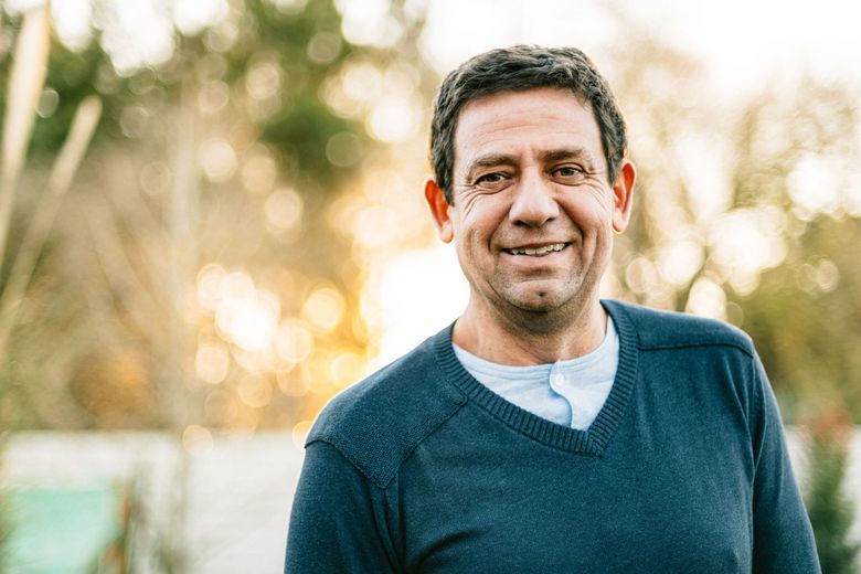 A man in a blue sweater is smiling for the camera.