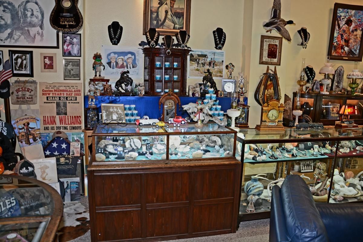 Interior of a shop filled with antique display cases, decorative objects, and artwork on the walls.