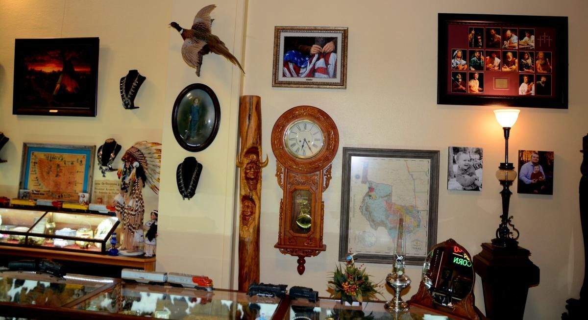 Display wall with art, clock, and photographs; a curio cabinet with items is visible below.