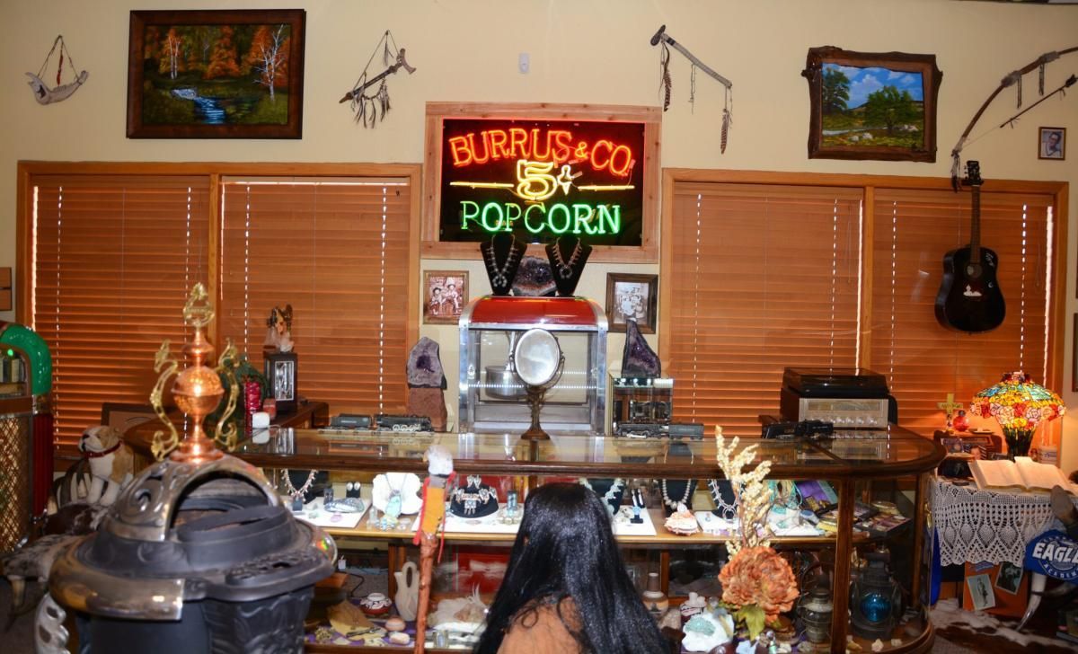 Interior shot of a room with a popcorn sign, display case, and various artifacts. A person stands facing away from the camera.