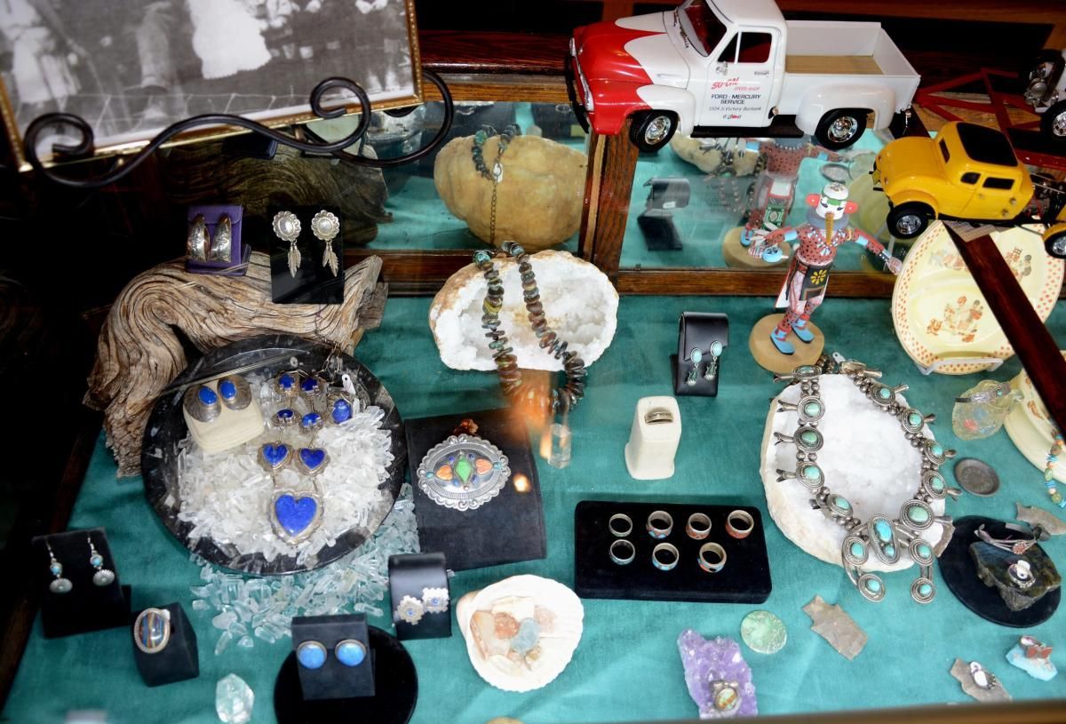 Display case with turquoise jewelry, small trucks, and old photograph.