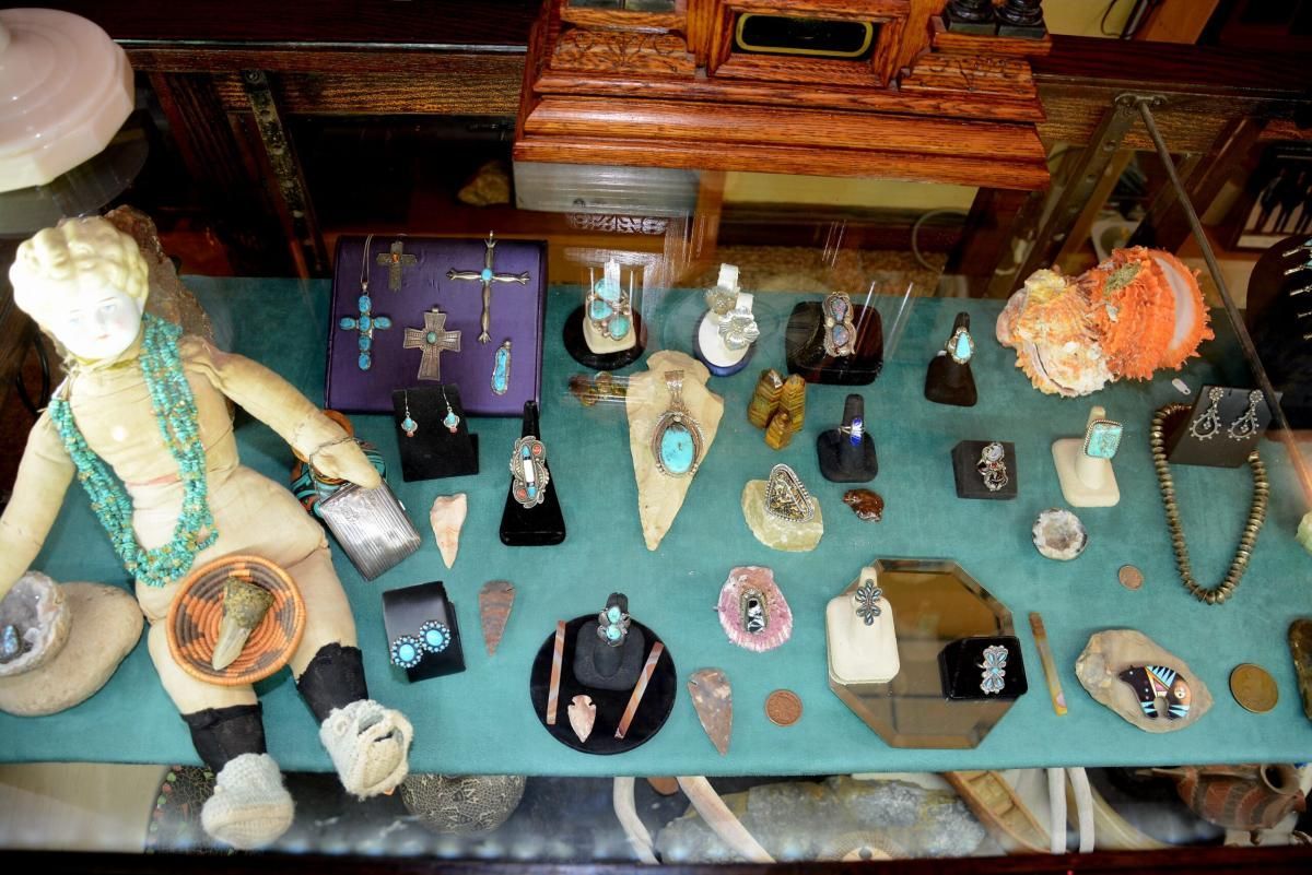 Jewelry display case with turquoise necklaces, earrings, and pendants; a doll sits on the left.